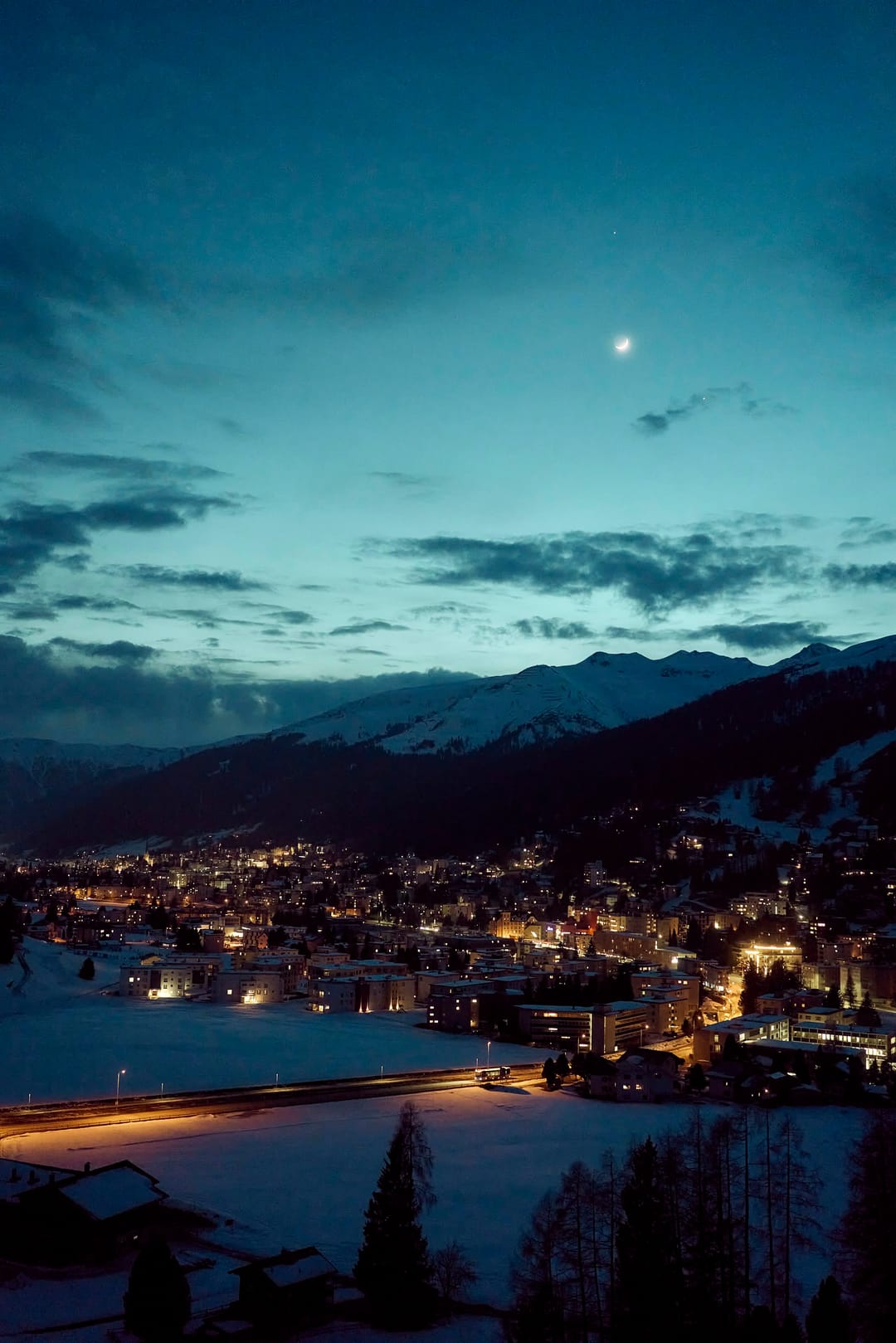 Davos bei Nacht, dahinter die Berge
